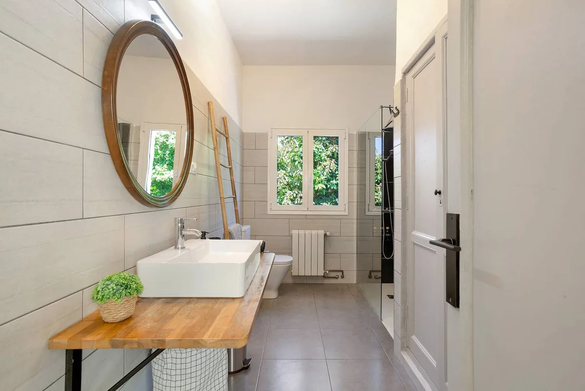 Salle de bains de Picarus Home avec vasque sur plan en bois, miroir rond et douche