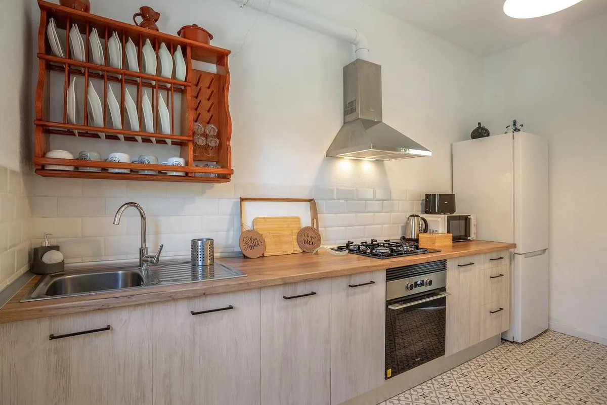 Cuisine équipée de Picarus Home avec plan de travail en bois, four, plaque de cuisson et égouttoir à assiettes