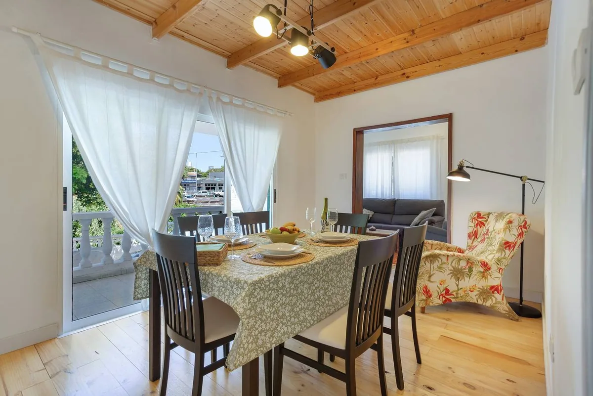 Salle à manger de Picarus Home avec la table dressée sous le plafond en bois et la porte ouverte sur la terrasse