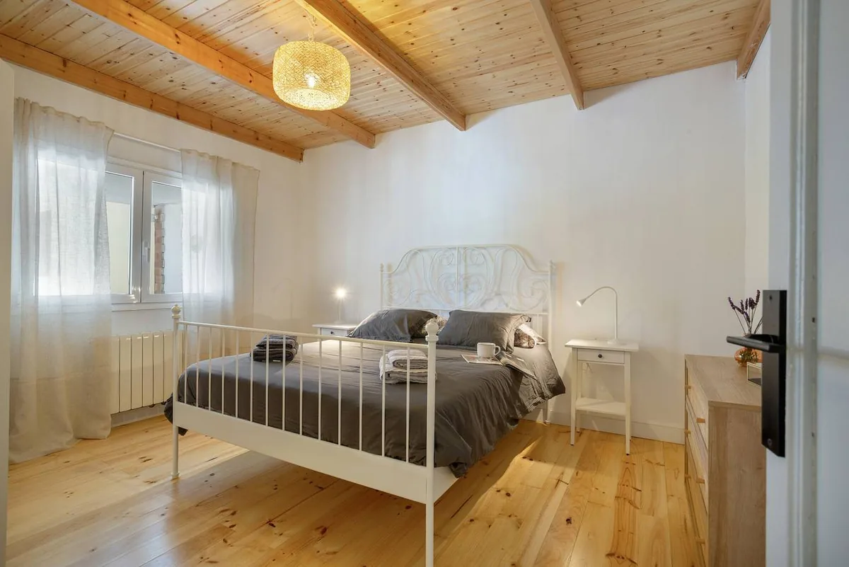 Deuxième chambre de Picarus Home avec un lit en fer forgé blanc et une fenêtre sur le jardin