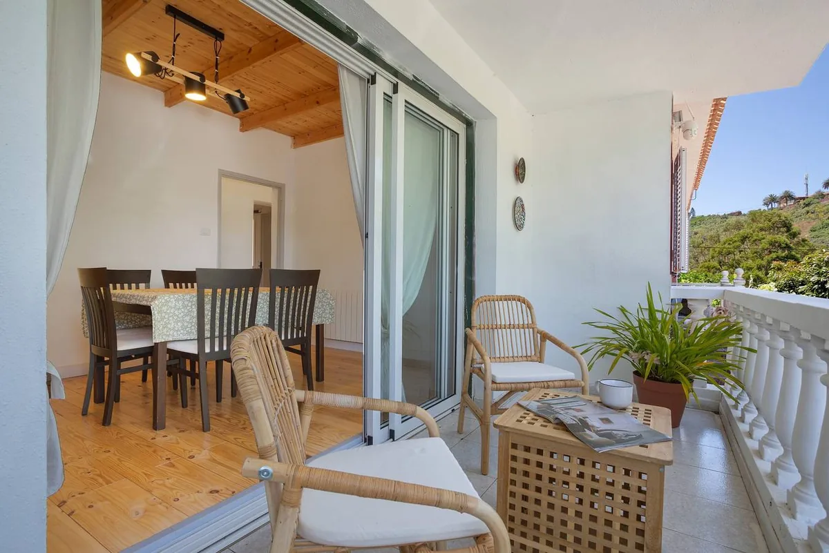 Terrasse couverte de Picarus Home avec une table à manger et des fauteuils en osier près du salon